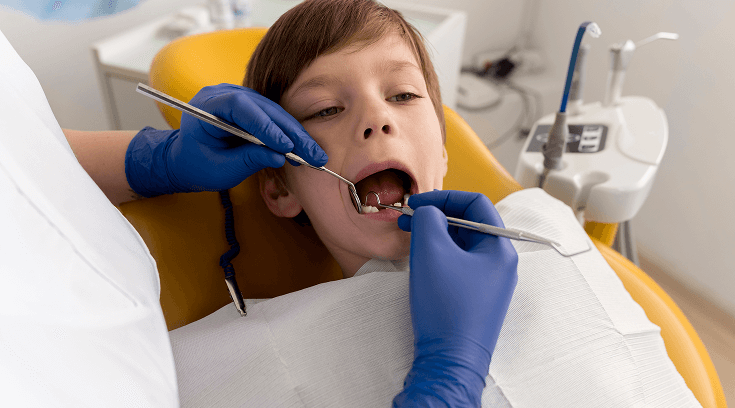 a dental mirror and probe to examine a young boy's teeth during a checkup.